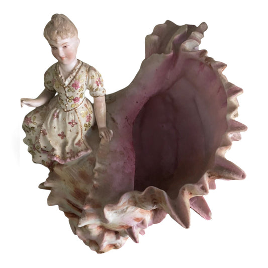 Figura antigua caracola porcelana biscuit mujer en vestido floreado apoyada en gran concha rosa